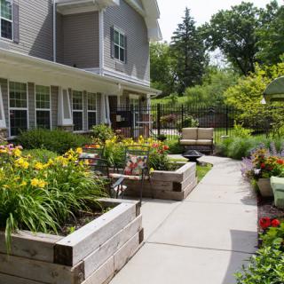 A beautifully landscaped garden with raised flower beds and a paved walkway.