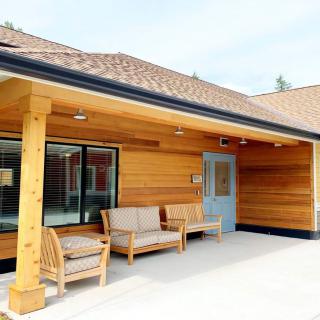A modern wooden building with a cozy patio area featuring outdoor seating.