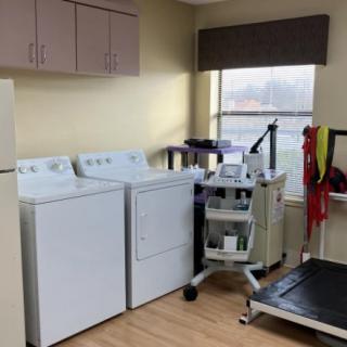 A room featuring washing machines, a dryer, and medical equipment including a treadmill.