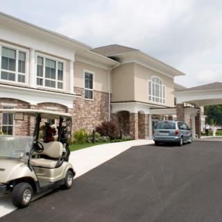 A residential building with a driveway, featuring a car and a golf cart parked outside.