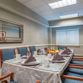 A neatly arranged dining room with a table set for a meal, featuring plates, cups, and folded napkins.