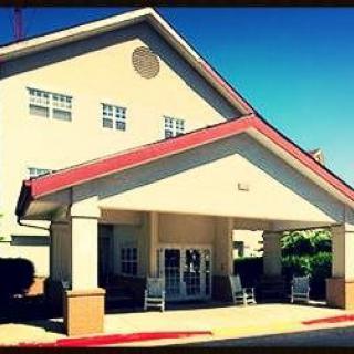 A sunny view of a building entrance with a red roof and columns.