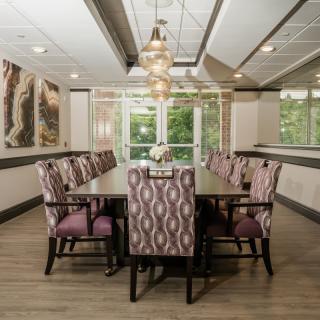 A modern dining room with elegant chairs and a stylish chandelier, featuring large windows for natural light.