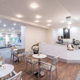 A modern cafe interior with tables, chairs, and a coffee station.