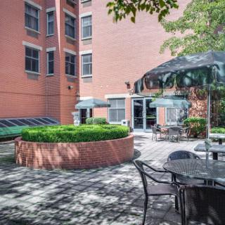 A serene courtyard featuring outdoor seating surrounded by greenery and a modern building backdrop.
