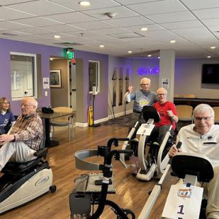 Elderly individuals participating in a group exercise session on stationary bikes.