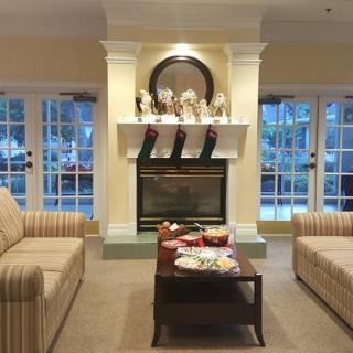 A cozy living room with a fireplace, two sofas, and a coffee table, beautifully decorated for the holidays.