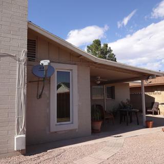 A residential house with a patio and satellite dish on a sunny day.