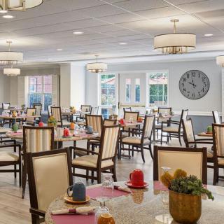 An elegant dining room with neatly arranged tables and chairs, featuring modern chandeliers and stylish decor.