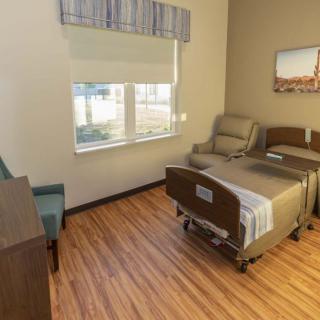 A clean and well-organized hospital room with a bed, chair, and window.