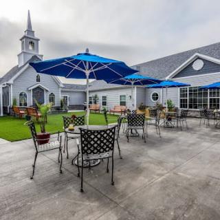 A spacious patio with tables and umbrellas near a church building.