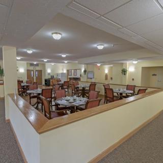 A spacious dining area with neatly arranged tables and chairs under warm lighting.