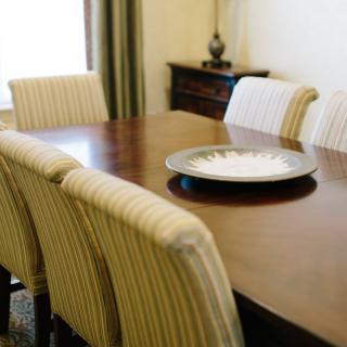 A neatly arranged dining room featuring a wooden table with striped chairs and a decorative centerpiece.