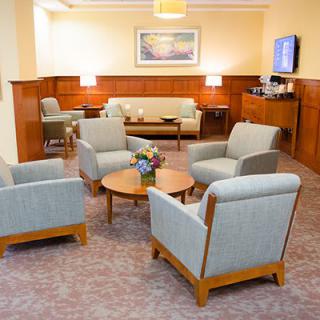 A comfortable waiting room with armchairs and a sofa arranged around a wooden coffee table.