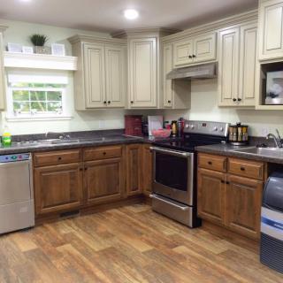 A modern kitchen with wooden and cream cabinets, stainless steel appliances, and a hardwood floor.