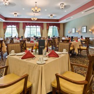 A well-appointed dining room with elegantly set tables and chandeliers.