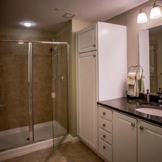 A modern bathroom featuring a glass-enclosed shower, vanity with a sink, and illuminated mirror.