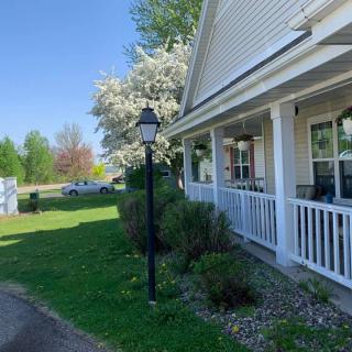 A charming house with a front porch and blooming trees on a sunny day.