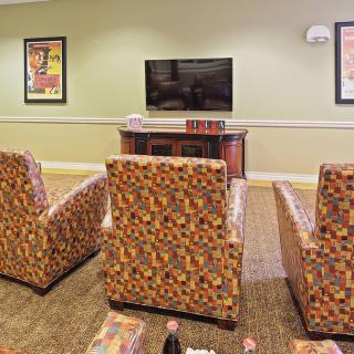 A cozy living room setup with patterned chairs facing a wall-mounted television.