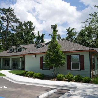 A charming residential house surrounded by trees under a partly cloudy sky.