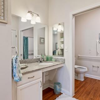 A bathroom featuring a modern vanity with a large mirror, well-lit by overhead lights.