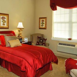 A cozy bedroom with red bedding and elegant decor.