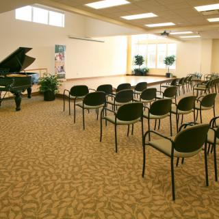 An indoor concert hall with a grand piano, seating area, and stage.