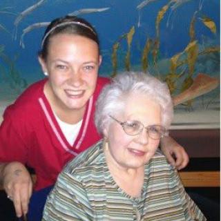 A caregiver and an elderly woman smiling together indoors.