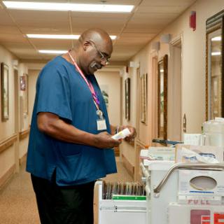 A healthcare professional reviewing notes in a hospital hallway.