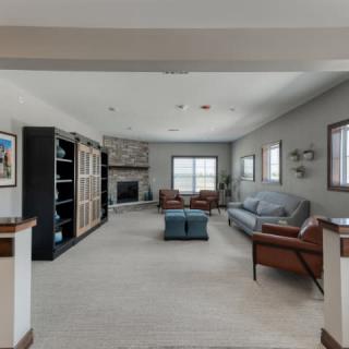 A spacious living room with a modern design featuring a fireplace, comfortable seating, and large windows.