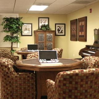 A cozy conference room with comfortable chairs, a laptop on the table, and decorative artwork on the walls.