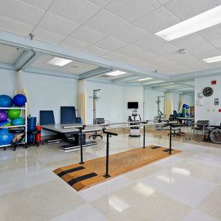 A well-equipped physical therapy and rehabilitation room with exercise equipment and parallel bars.