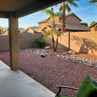 A serene backyard with desert landscaping, featuring a patio area and palm tree.
