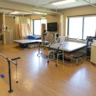 A physical therapy room equipped with exercise tables and parallel bars.