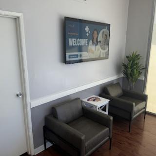 A modern waiting room with comfortable seating and a TV.