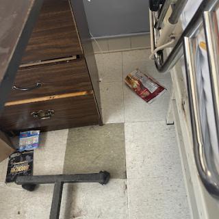 A kitchen scene showing a disorganized floor with a box and furniture.