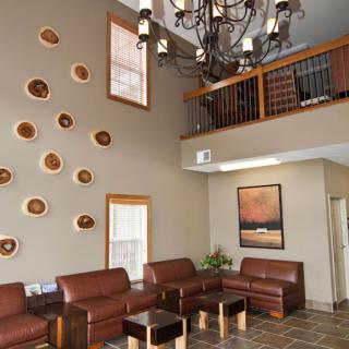 A modern lobby featuring comfortable leather seating, decorative wall elements, and a stylish chandelier.