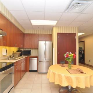 A modern kitchen featuring stainless steel appliances, wood cabinets, and a round table adorned with flowers.