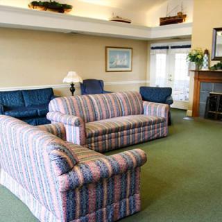 A cozy living room with striped sofas, a fireplace, and a carpeted floor.