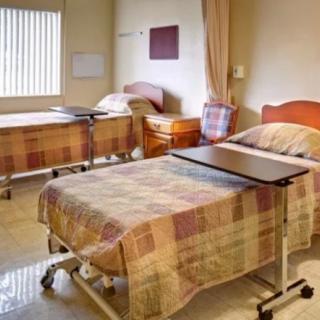 A hospital room with two neatly arranged beds and bedside tables.