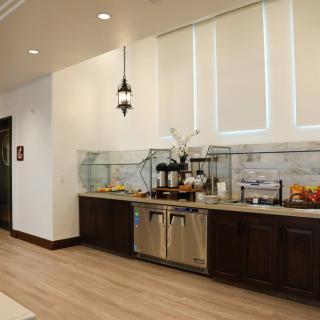 A modern buffet setup with various food and drink options on a countertop, featuring sleek cabinets and bright interior design.