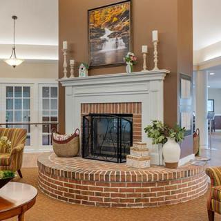 A cozy living room featuring a brick fireplace adorned with candles and plants.