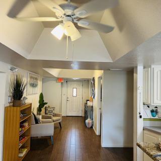 A modern hallway with wood flooring, a ceiling fan, and contemporary decor.