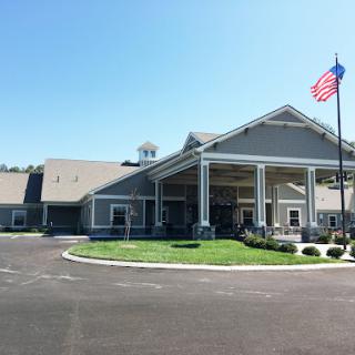 A welcoming entrance to a community facility with manicured landscaping and an American flag waving in the breeze.
