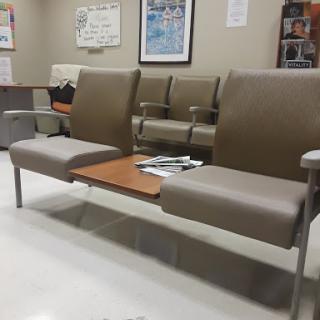 A view of a waiting area featuring padded chairs and a small table.
