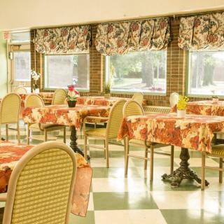 A cozy dining room with floral tablecloths and checkered flooring.