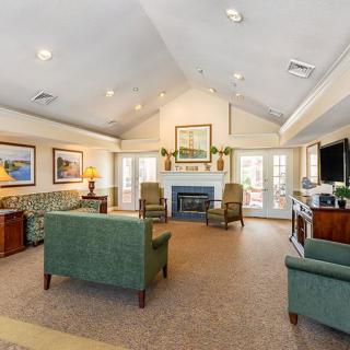 A spacious and elegantly decorated living room with sofas, chairs, a fireplace, and artwork on the walls.
