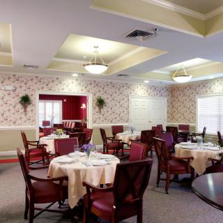 An elegant dining room setup with multiple tables and chairs, featuring stylish lighting and decor.