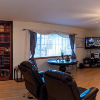 A cozy living room with leather armchairs, a television, and a large window adorned with curtains.