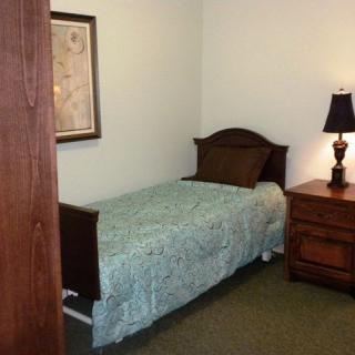 A cozy bedroom with a single bed, nightstand, and lamp.